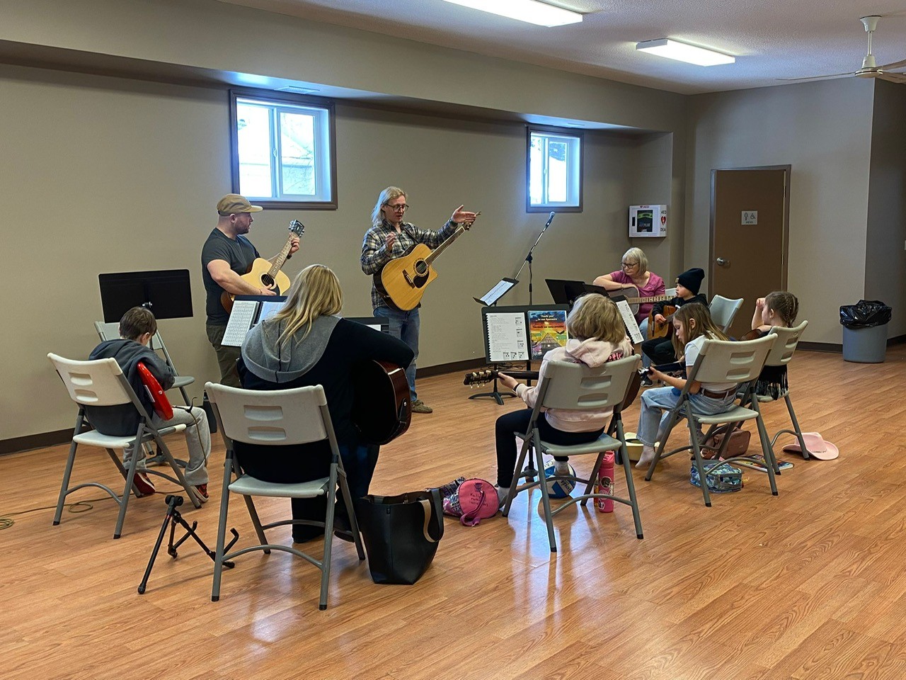 The whole guitar class being instructed in guitar. Many stands, books and guitars visible.