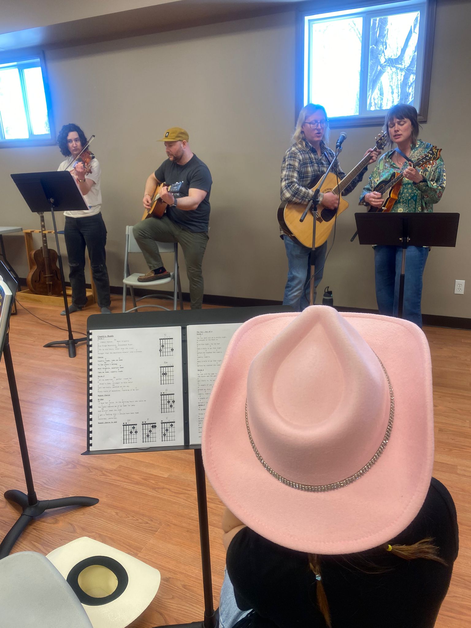 The Conjuring Creek Music Society house band, two guitars, a mandolin and a violin. A participant in a pink cowboy hat is playing along.